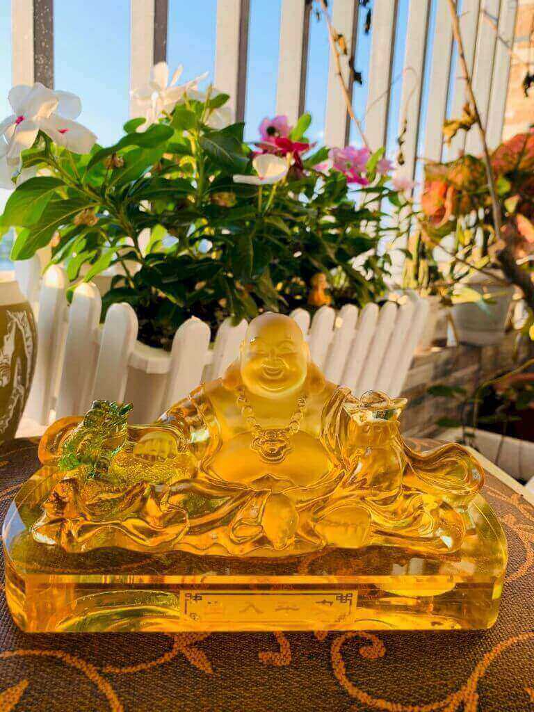 Tượng Phật Di Lặc ngồi bên bao tiền bằng chất liệu lưu ly màu vàng